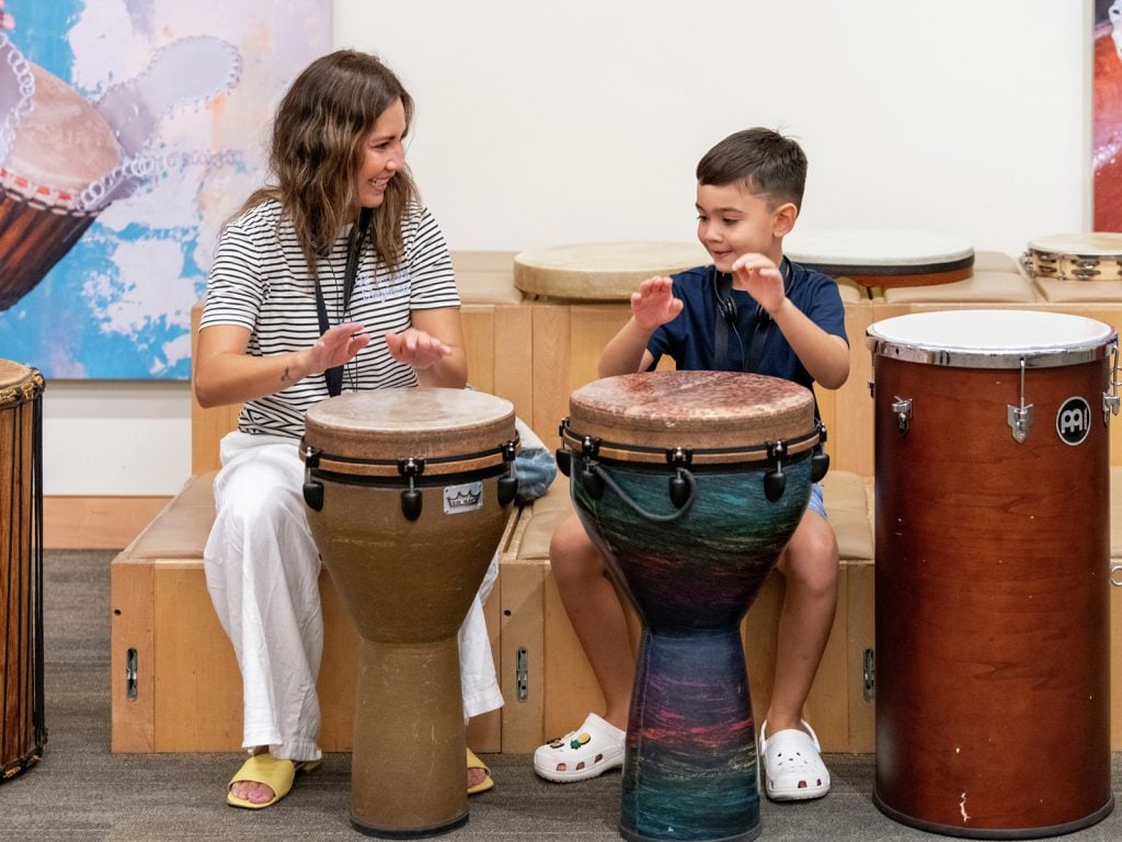 Two guests drumming in the Experience Gallery