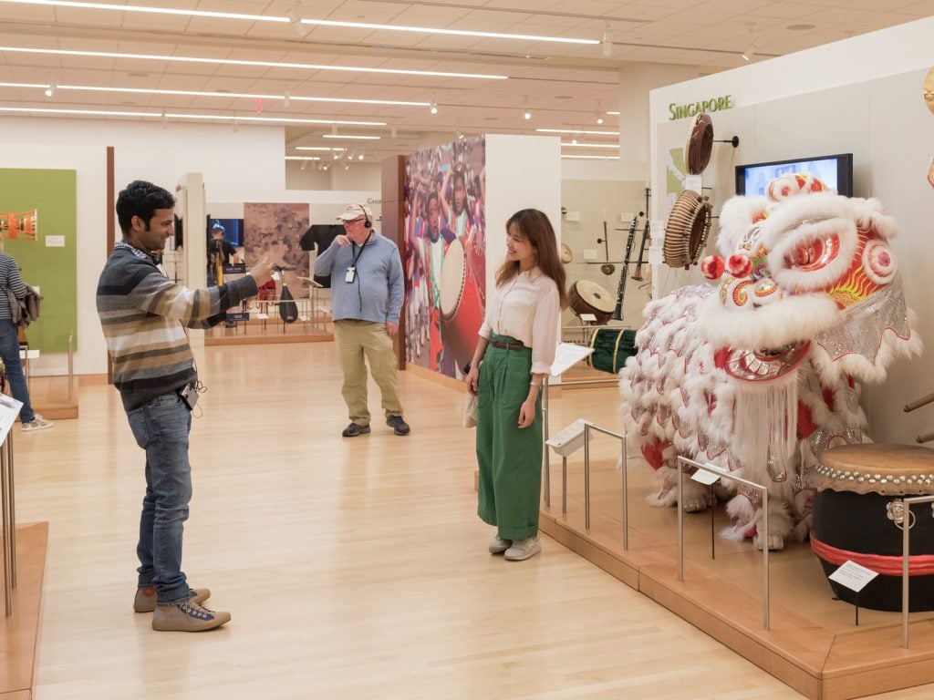 A guest takes a photo in front of the Singapore Exhibit in the Asia Gallery