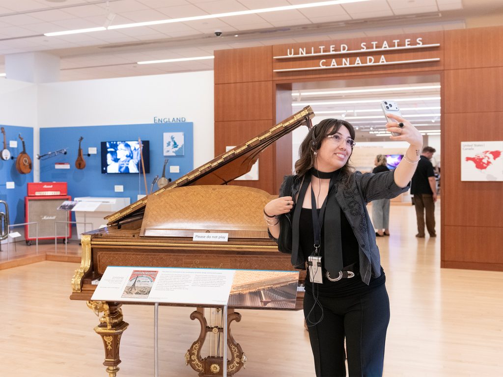 A guest takes a selfie in front of the Erard grand piano in the Europe Gallery