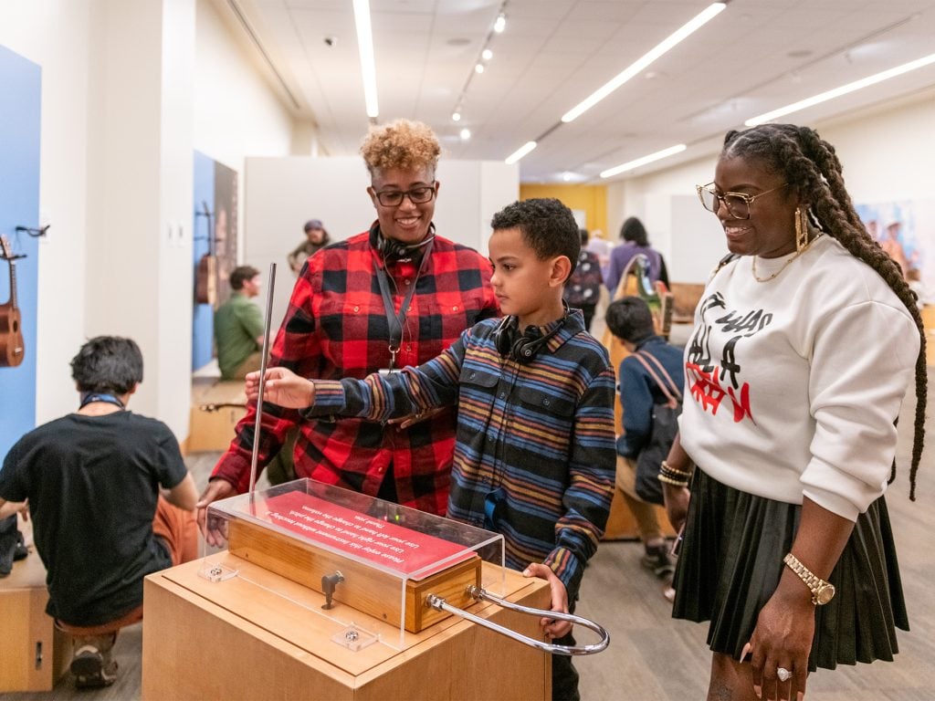 Guests smile as they play the theremin in the Experience Gallery