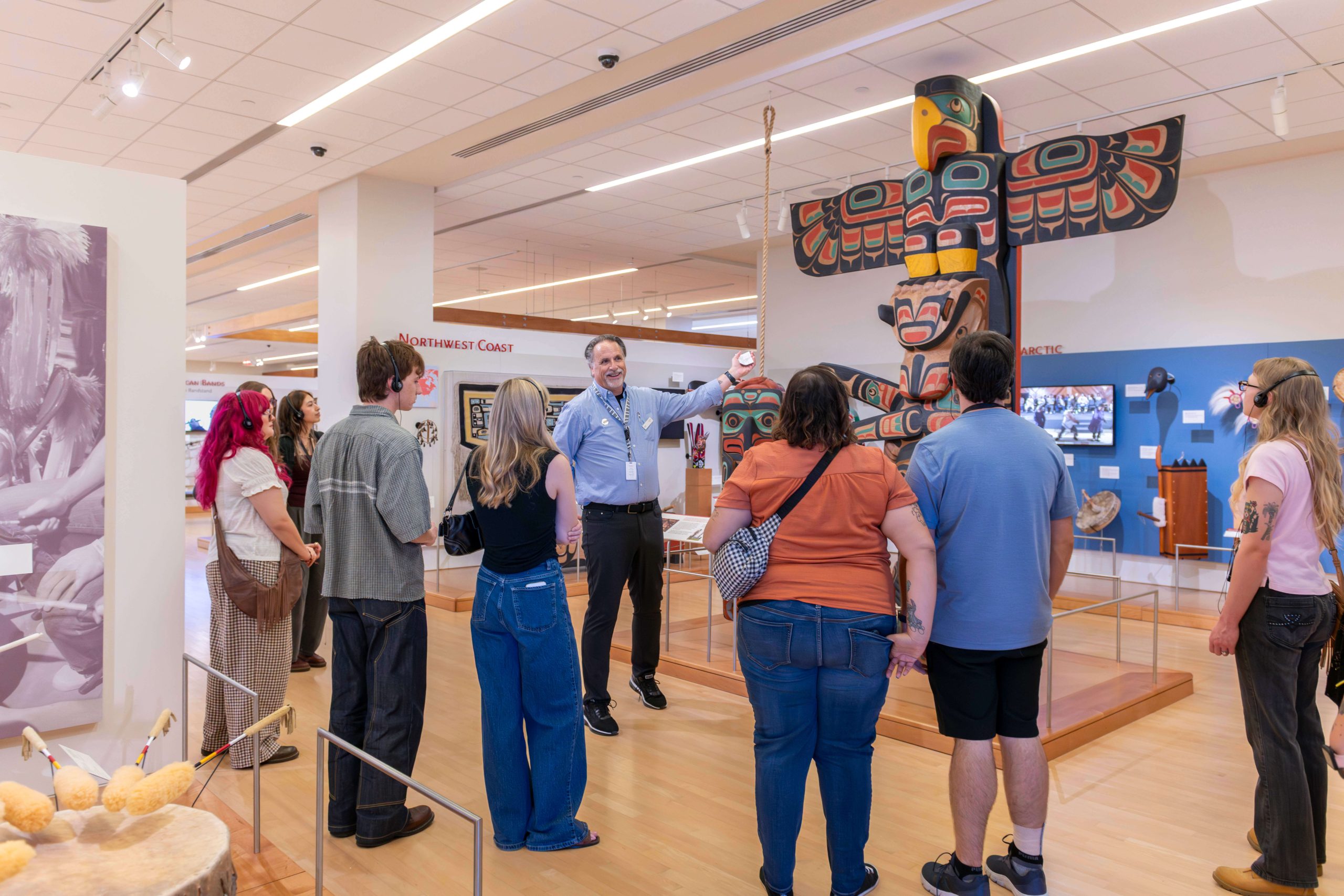 Museum guide John Carey shows guests the Kwakwaka’wakw totem pole in MIM’s United States / Canada Gallery.