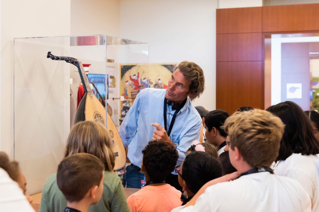 Museum guide Bill Brand tells field trip students about a Turkish oud in the Middle East and North Africa Gallery.