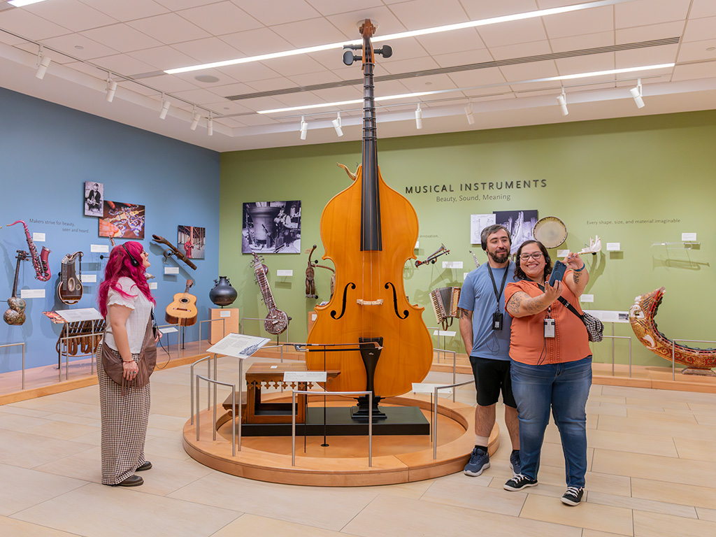Guests take a selfie in front of the octobass in MIM’s Orientation Gallery
